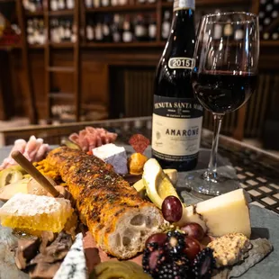 a platter of cheese, crackers, olives, and a bottle of wine