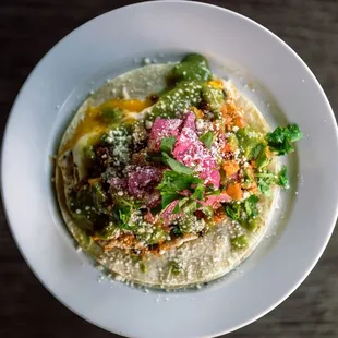 a taco with vegetables and cheese on a white plate