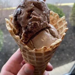a hand holding a cone of ice cream