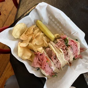 Half a Leave it to Beefer sandwich served with chips and a pickle.