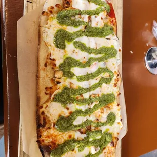 a pizza covered in pesto sauce
