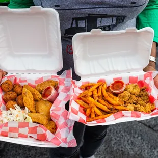 a man holding two trays of food