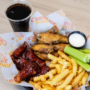 a basket of chicken wings, fries, celery, and a drink