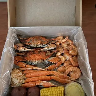 a box of crab legs, corn and potatoes