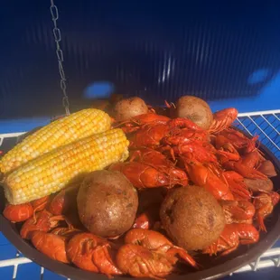 a plate of crawfish, corn and potatoes