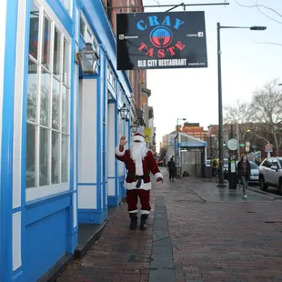 a man dressed as santa claus walking down a sidewalk