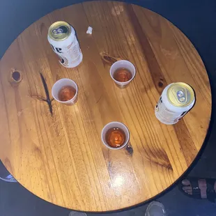 a person standing at a table with cups of beer