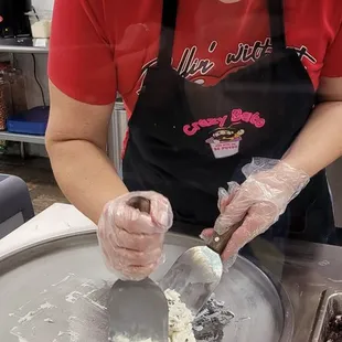 a woman in an apron making doughnuts