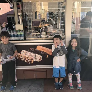 three children standing in front of a donut shop