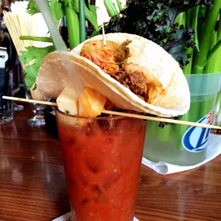 Pork Kimchi Bloody Mary with a cheese skewer, green onion, celery, and kale.