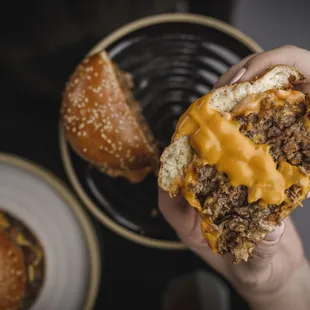 a hand holding a cheeseburger