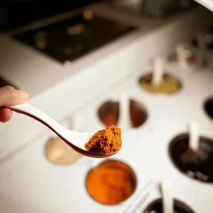 a hand holding a spoon full of hot pot sauce