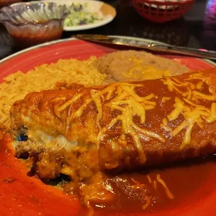 Chimichanga with red sauce and a side of rice and beans.