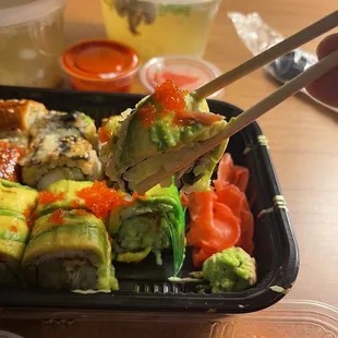 a tray of sushi with chopsticks