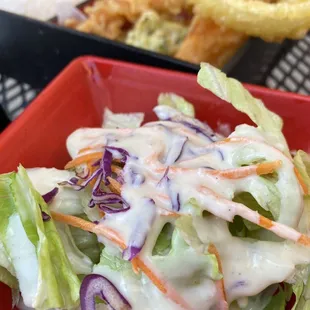 a bowl of salad and a bottle of beer