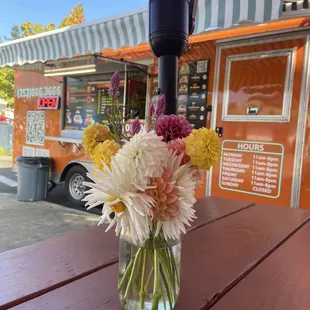 a vase of flowers in front of a taco truck