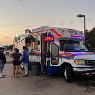 a group of people standing in front of a taco truck