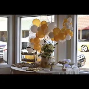 a table with balloons and a vase of flowers