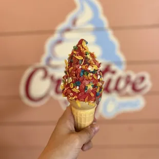 a hand holding an ice cream cone with sprinkles