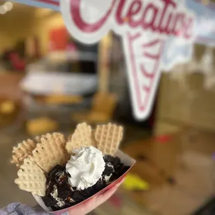 a hand holding a cone of ice cream and waffles