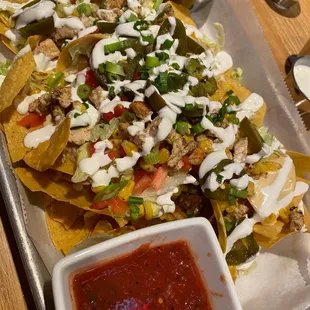 a tray of nachos and a bowl of salsa