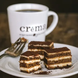 a piece of cake on a plate next to a cup of coffee