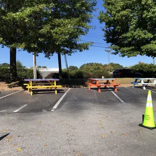 Part of the parking lot is blocked off and picnic benches placed there.