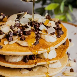 a stack of pancakes being drizzled with syrup