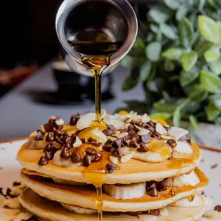 a stack of pancakes being drizzled with syrup
