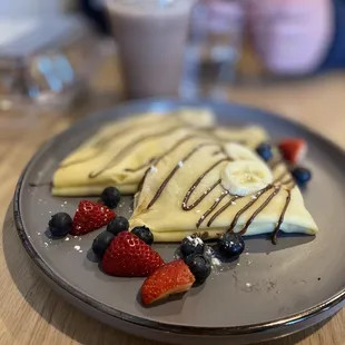 a plate of crepes with strawberries and blueberries