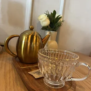 a teapot and a glass cup on a wooden tray