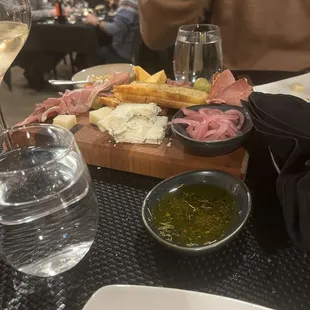 a plate of meat, bread, and a glass of wine