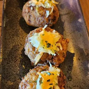 three crab cakes on a black plate