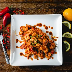 a plate of shrimp with chili sauce and lemons