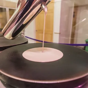 a close up of a crepe being poured onto a pan