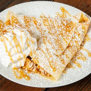 a plate of crepes with whipped cream and caramel sauce