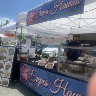 a man standing behind a food stand
