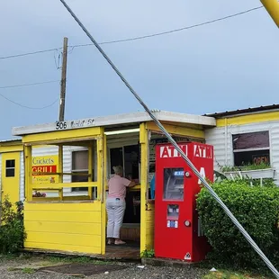 a woman standing in the doorway of a yellow and white building