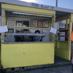 a man standing in front of a yellow kiosk