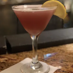 a pink cocktail with a lemon wedge