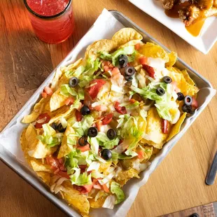 Tortilla chips topped with shredded lettuce * diced tomatoes sautéed onions* green peppers * sliced olives ,shredded mozzarella and cheddar