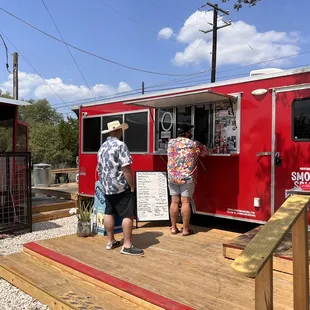 man and a woman standing in front of a red food truck