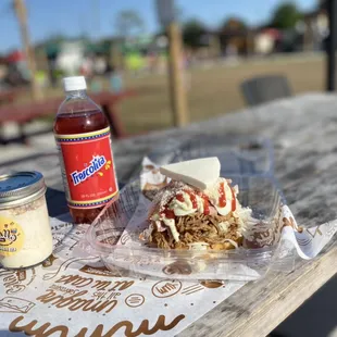 a picnic table with a bottle of syrup and a sandwich