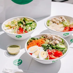 three bowls of salad with dressing