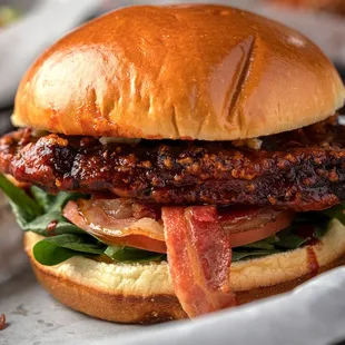 a burger with bacon and lettuce on a bun