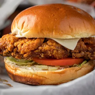 a fried chicken sandwich with lettuce, tomato, and cheese