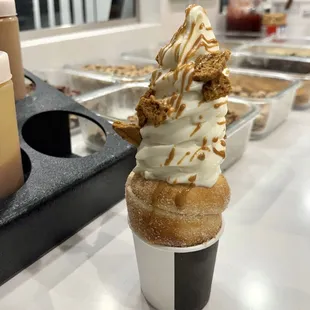 Vanilla soft serve with biscoff syrup, drizzle and crumbles in a cinnamon sugar cone