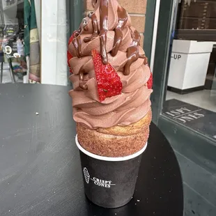 a cup of chocolate frosting with strawberries on top