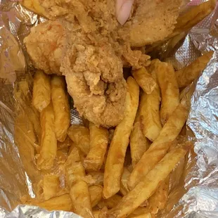 a person grabbing a piece of fried chicken