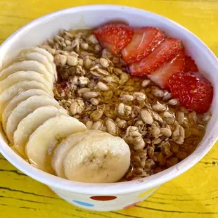 a bowl of granola with sliced bananas and strawberries